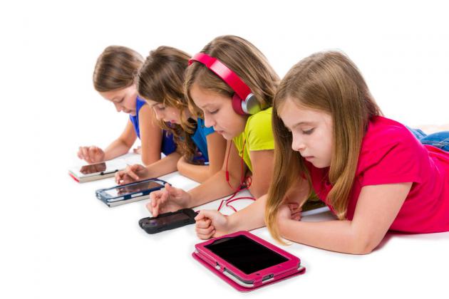 Four children playing electronic devices