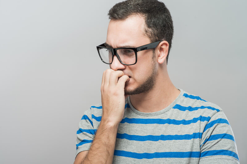 anxious man biting nails worried