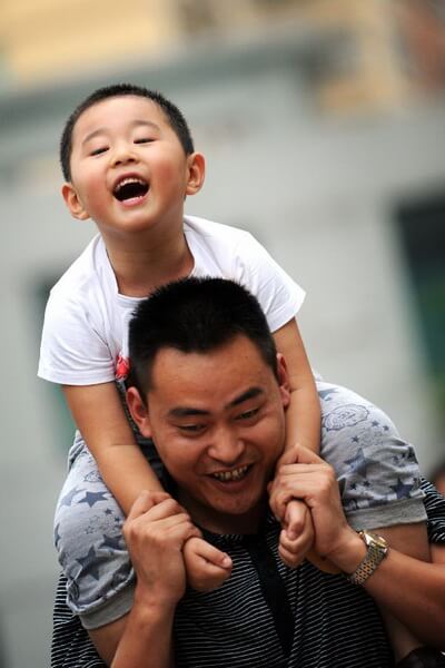 A Chinese dad with his son on his shoulder