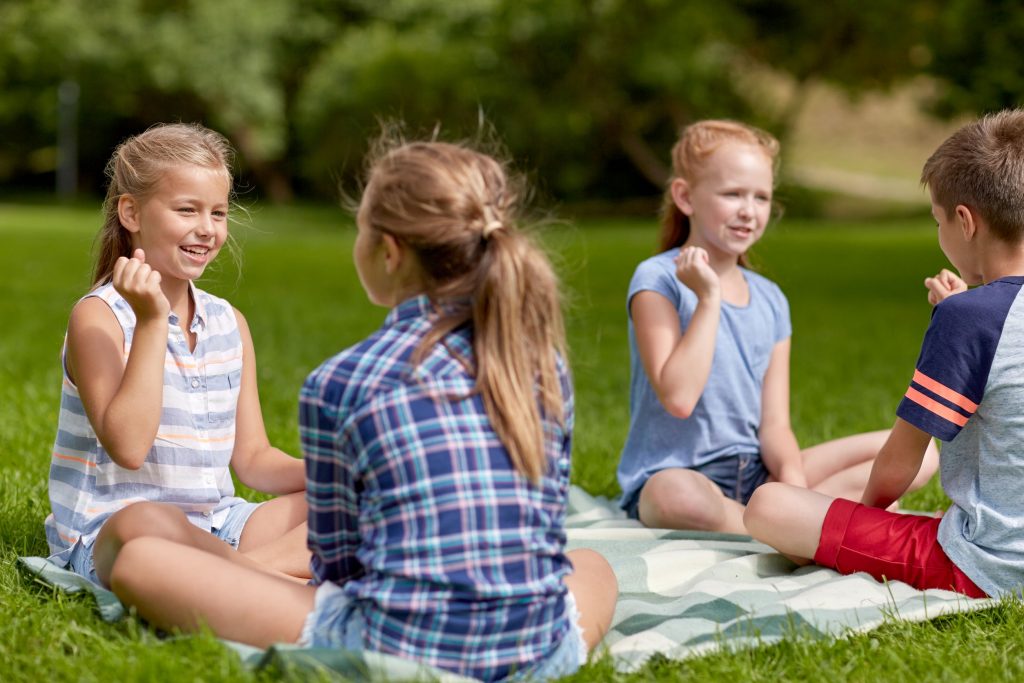 Summer holidays, entertainment, childhood, leisure and people concept - group of happy pre-teen kids playing rock-paper-scissors game in park